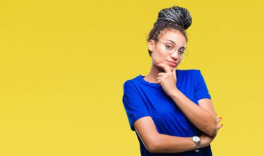 Genç saç Afro-Amerikan Kız emin çapraz kollar ve çeneme kaldırdı el ile gülümseme ile kameraya bakarak izole arka plan üzerinde gözlük takan örgülü. Pozitif düşünce.