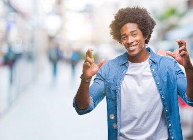 Umut ve gözleri kapalı geçiş parmaklarıyla gülümseyen izole arka plan üzerinde Afro Amerikalı adam. Şans ve batıl kavramı.