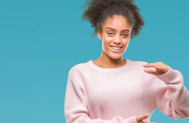 Üzerinde kış kazak giyen genç afro Amerikan kadın arka plan ile büyük ve büyük boy işaret, ölçü birimi sembol gösteren el eller izole. Kameraya bakarak gülümsüyordu. Ölçüm kavramı.