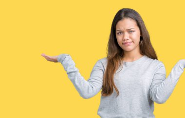 İzole arka plan clueless ve şaşkın bir ifadeyle kollar ve eller kaldırdı üzerine kazak giyen genç güzel esmer kadın. Şüphe kavramı.