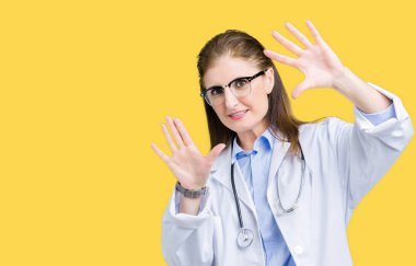 Tıbbi kat izole üzerinde giyen orta yaş olgun doktor kadın arka plan kullanarak el avuç içi ve parmaklar, kamera perspektif çerçevesini yapıyor gülen