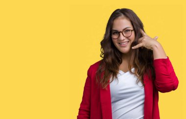 Artı boyutu genç iş kadını zarif ceket ve gözlük yapıyor gülümseyen izole arka plan üzerinde giyen güzel telefon hareketi ile el ve parmak telefonda konuşuyor gibi. Kavramları iletişim.