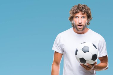 Futbol futbol topu izole arka plan üzerinde bir sürpriz yüz, korkuyor ve heyecanlı korku ifadesi ile şok korkmuş tutan Latin asıllı yakışıklı modeli