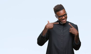 Genç Afro-Amerikan rahip adam kendinden emin gösterilen ve işaret parmakları diş ve ağız ile gülümseyen izole arka plan üzerinde. Sağlık kavramı.