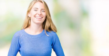 Mavi kazak izole üzerinde giyen güzel genç kadın arka plan gülen ve komik deli şaka çünkü yüksek sesle zor gülüyor. Mutlu ifade.