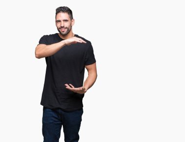 Yakışıklı delikanlı ile büyük ve büyük boy işaret, ölçü birimi sembol gösteren el eller izole arka plan üzerinde. Kameraya bakarak gülümsüyordu. Ölçüm kavramı.