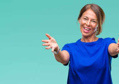 Orta yaş İspanyol kadın kıdemli sarılmak için kollarını açarak gülümseyerek kameraya bakarak izole arka plan üzerinde. Neşeli ifade kucaklayan mutluluk.