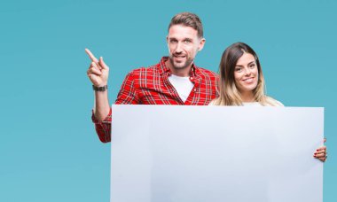 Genç çift birlikte holding boş afiş üzerinde izole arka tarafına el ve parmak ile işaret çok mutlu