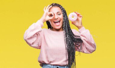 Mutlu yüz el parmaklarının arasından seyir göz üzerinde ok işaretiyle yapıyor gülümseyen izole arka plan üzerinde pembe çörek yeme genç Afro-Amerikan Kız