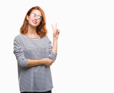 İzole arka plan mutlu yüz zafer işareti yaparken kameraya göz kırpıyor ile gülümseyen gözlüklü genç güzel kadın. İki numaralı.