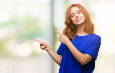 Gülümseyen ve iki elleri ve parmakları ile tarafına işaret kamera bakarak izole arka plan üzerinde genç güzel kadın.