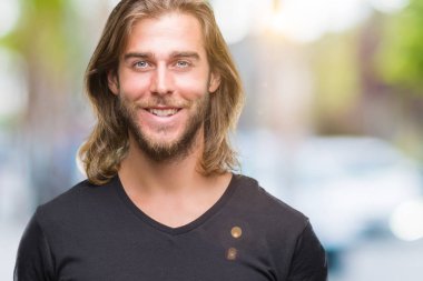 İzole arka plan ile bir mutlu ve serin üzerinden uzun saçlı yakışıklı delikanlı yüzündeki gülümseme. Şanslı kişi.