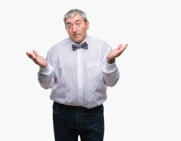 ハンサムな年配の男性は 腕と手を上げて分離背景無知と混乱する式で蝶ネクタイを着用します 疑いのコンセプト — ストック写真