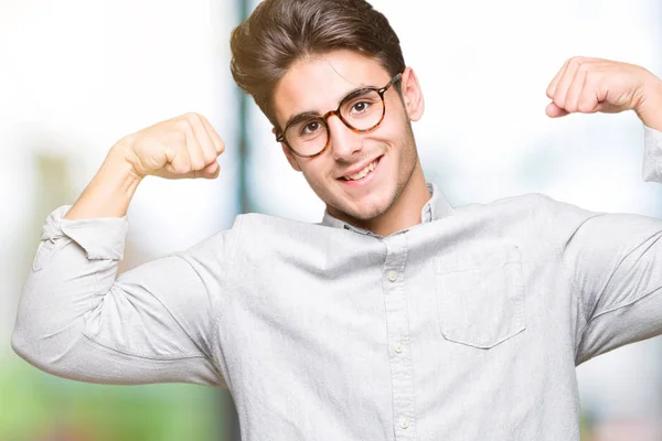 年轻英俊的男人戴着眼镜在孤立的背景显示手臂肌肉微笑自豪 健身理念 — 图库照片