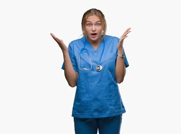 年轻的高加索医生妇女穿着外科医生制服在孤立的背景庆祝疯狂和惊讶的成功与手臂抬起和睁开眼睛尖叫兴奋 优胜者概念 — 图库照片