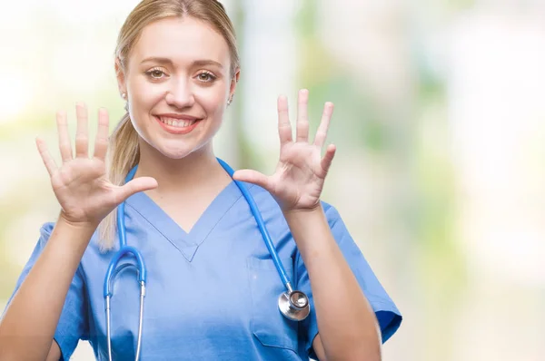 年轻的金发医生的妇女在孤立的背景显示和指向九的手指 而微笑着自信和快乐 — 图库照片