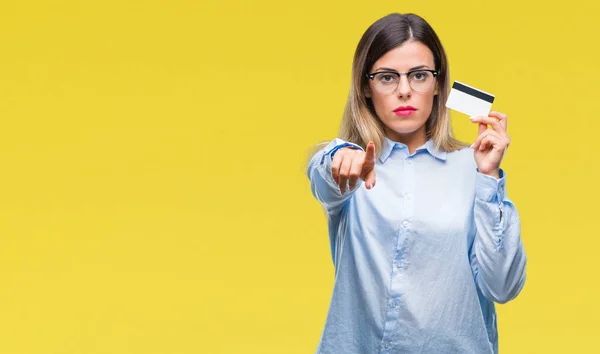 Young beautiful business woman holding credit card over isolated background pointing with finger to the camera and to you, hand sign, positive and confident gesture from the front