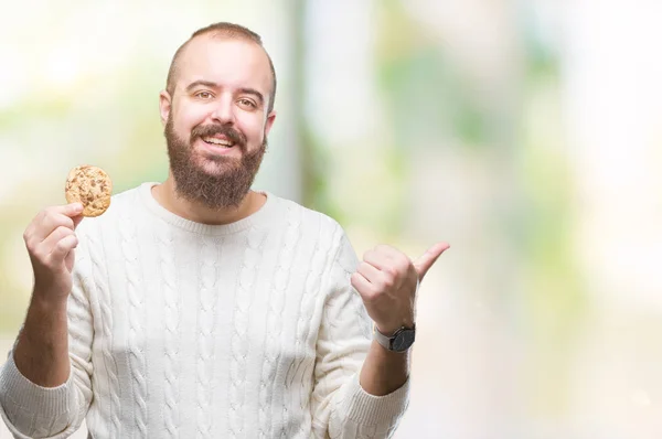 Junger Hipster Mann Isst Schokoladenkeks Über Isoliertem Hintergrund Und Zeigt — Stockfoto