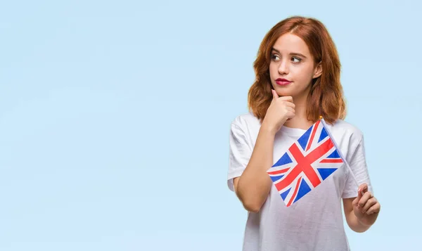 英国年轻美丽的女子拿着国旗在孤立的背景严肃的面孔思考问题 非常困惑的想法 — 图库照片