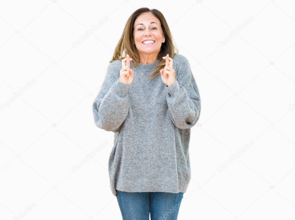 Beautiful middle age woman wearing winter sweater over isolated background smiling crossing fingers with hope and eyes closed. Luck and superstitious concept.