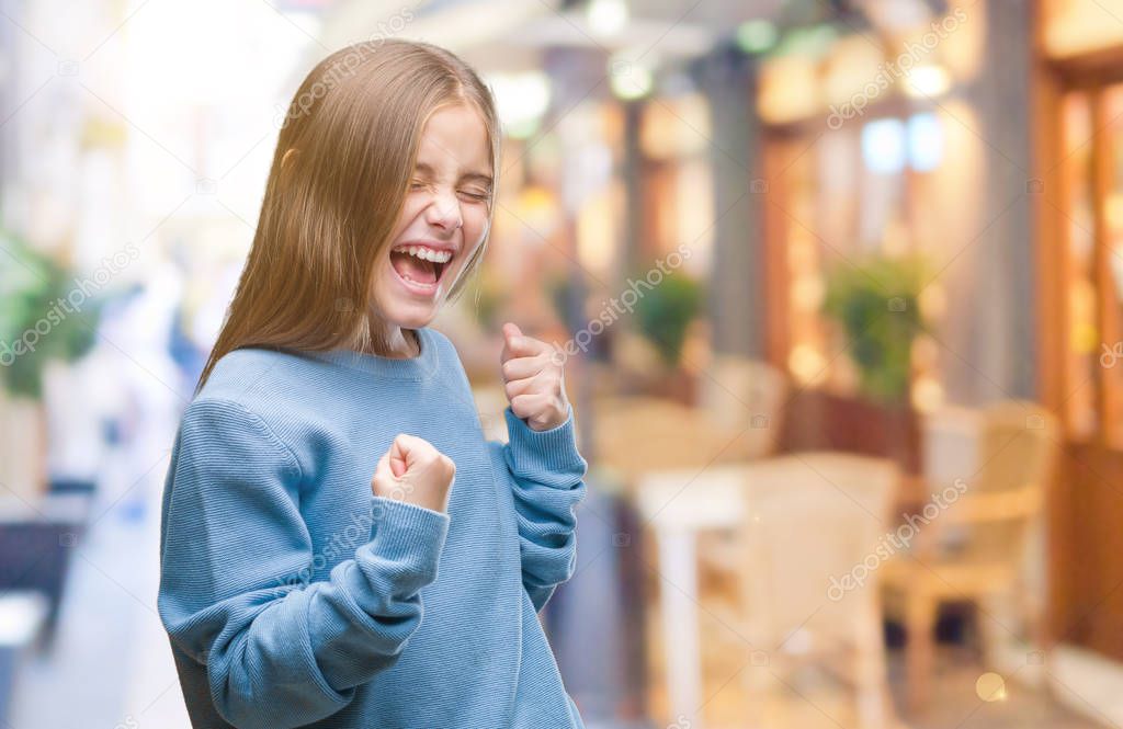 Young beautiful girl wearing winter sweater over isolated background very happy and excited doing winner gesture with arms raised, smiling and screaming for success. Celebration concept.