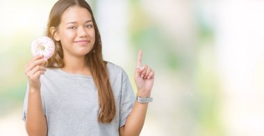 İzole arka bir fikir ya da soru işaret parmağı gülen yüz, bir numara ile sürpriz üzerinde pembe çörek yiyen genç güzel kadın