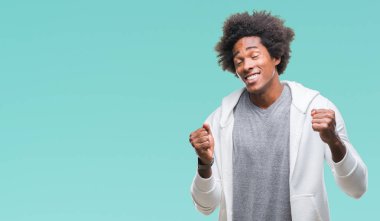 Üzerinde sweatshirt giyen Afro Amerikalı adam arka plan çok mutlu ve heyecanlı kaldırdı, silah ile kazanan jest yapıyor gülümseyen ve başarı için çığlık izole. Kutlama kavramı.