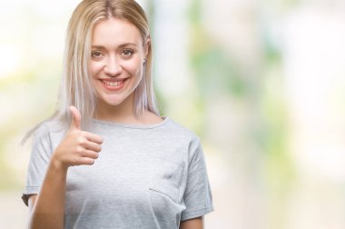 Genç Sarışın kadın hareketi el ile mutlu yaşasın yapıyor izole arka plan yüzünden. Kameraya bakarak başarı gösteren ile ifade onaylama.