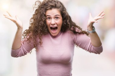 Güzel esmer kıvırcık saçlı Genç kız giyiyor pembe kazak üzerinde arka plan çılgın kutlama izole ve başarı için kaldırdı kollarını açarak hayret ve açık gözleri çığlık heyecanlı. Kazanan kavramı