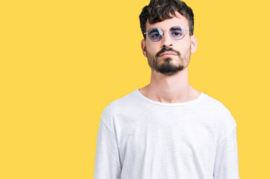 Genç yakışıklı adam yüzünde ciddi bir ifade ile izole arka plan üzerinde güneş gözlüğü takıyor. Basit ve doğal kameraya bakıyor.