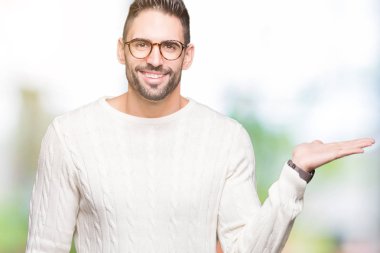 Neşeli sunulması ve kameraya bakarak avucunun ile işaret gülümseyen izole arka plan üzerinde gözlük takan genç yakışıklı adam.