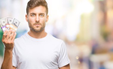 Acımak yüz ciddi düşünüyorum üstünde kendine güvenen bir ifade ile izole arka plan üzerinde dolar yığını tutan genç yakışıklı adam