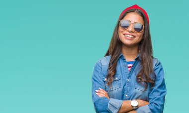 Genç güzel Arap kadın üzerinde güneş gözlüğü takıyor mutlu yüz ile gülümseyerek kameraya seyir silah geçti arka plan izole. Olumlu bir kişi.