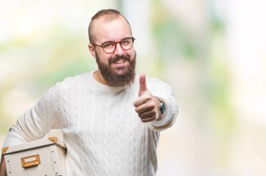 Hareketli genç hipster adam gözlük, hareketli kutusu izole arka plan üzerinde mutlu ok işareti yapıyor büyük gülümseme ile tutarak yukarı parmaklarıyla, mükemmel işareti başparmak