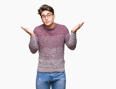 İzole arka plan clueless ve şaşkın bir ifadeyle kollar ve eller kaldırdı üzerinde gözlük takan yakışıklı delikanlı. Şüphe kavramı.