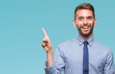 Kameraya bakarak yan el ve parmak ile işaret eden genç yakışıklı iş adamı yüzünde kocaman bir gülümseme ile izole arka plan üzerinde.