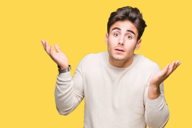 İzole arka plan clueless ve şaşkın bir ifadeyle kollar ve eller kaldırdı genç yakışıklı adam. Şüphe kavramı.