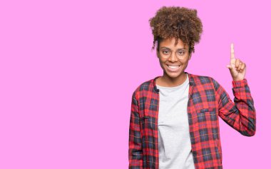 Güzel genç Afrikalı-Amerikalı kadın ve kendinden emin ve mutlu gülümseyerek süre parmak numaralı yukarıyı gösteren izole arka plan üzerinde gözlük.