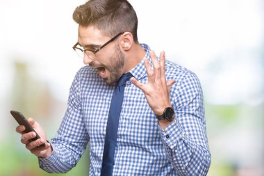 Genç iş adamı smartphone üzerinde kullanma büyük gülümseme ile çığlık zaferini kutluyor arka plan çok mutlu ve heyecanlı, kazanan ifade izole ve ellerini kaldırdı
