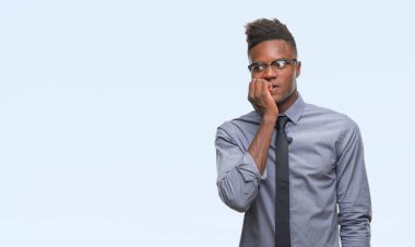 Stresli ve gergin elle çivi ısırma ağzına bakarak izole arka plan üzerinde genç Afro-Amerikalı iş adamı. Anksiyete sorunu.