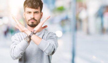 İzole arka plan ret ifade geçiş kollarına eksi işareti, kızgın surat yapıyor sweatshirt giyen genç yakışıklı adam