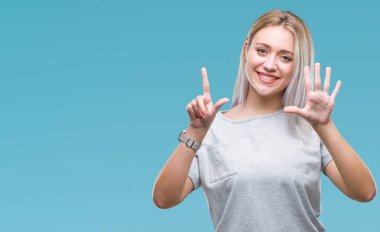 Genç Sarışın kadın gösterilen ve parmakları ile işaret izole arka plan yüzünden kendinden emin ve mutlu gülümseyerek süre yedi numara.