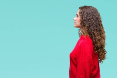 Güzel esmer kıvırcık saçlı Genç kız tarafına, seyir izole arka plan üzerinde gözlük ve kış kazak giyen dinlenmek doğal yüz emin gülümseme ile pozuyla profil.