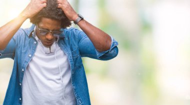 Çünkü çaresiz ve stresli baş ağrısı acı izole arka plan üzerinde müzik kulaklık giyen Afro Amerikalı adam ağrı ve migren. Ellerini kafasına.
