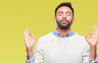 Yetişkin İspanyol adam giyen kış kazak izole arka plan üzerinde dinlenmek ve gülümseyen gözlerle kapalı parmak jestle meditasyon yapıyor. Yoga kavramı.