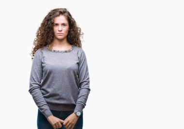 Güzel esmer kıvırcık saçlı Genç kız yüzünde ciddi bir ifade ile izole arka plan üzerinde bir kazak giyiyor. Basit ve doğal kameraya bakıyor.