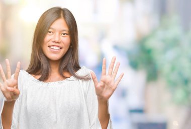 Genç Asyalı kadın gösterilen ve parmakları ile işaret izole arka plan üzerinde numara 9 kendinden emin ve mutlu gülümseyerek süre.