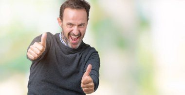 El ile pozitif jest yapıyor onaylama izole arka plan üzerinde bir kazak giymiş yakışıklı orta yaş komuta sizde başparmak gülümseyen ve başarı için mutlu. Kamera, kazanan jest arıyorsunuz.