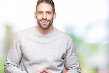 Üzerine tişört giyen genç yakışıklı adam arka plan eller birlikte izole ve rahat ve neşeli gülümseyen parmak çarpı işareti. Başarı ve iyimser