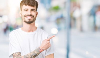 Beyaz t-shirt üzerinde izole giyen genç yakışıklı adam reklam, ciddi ve sakin yüz gösterilen yan el parmak ile işaret arka plan